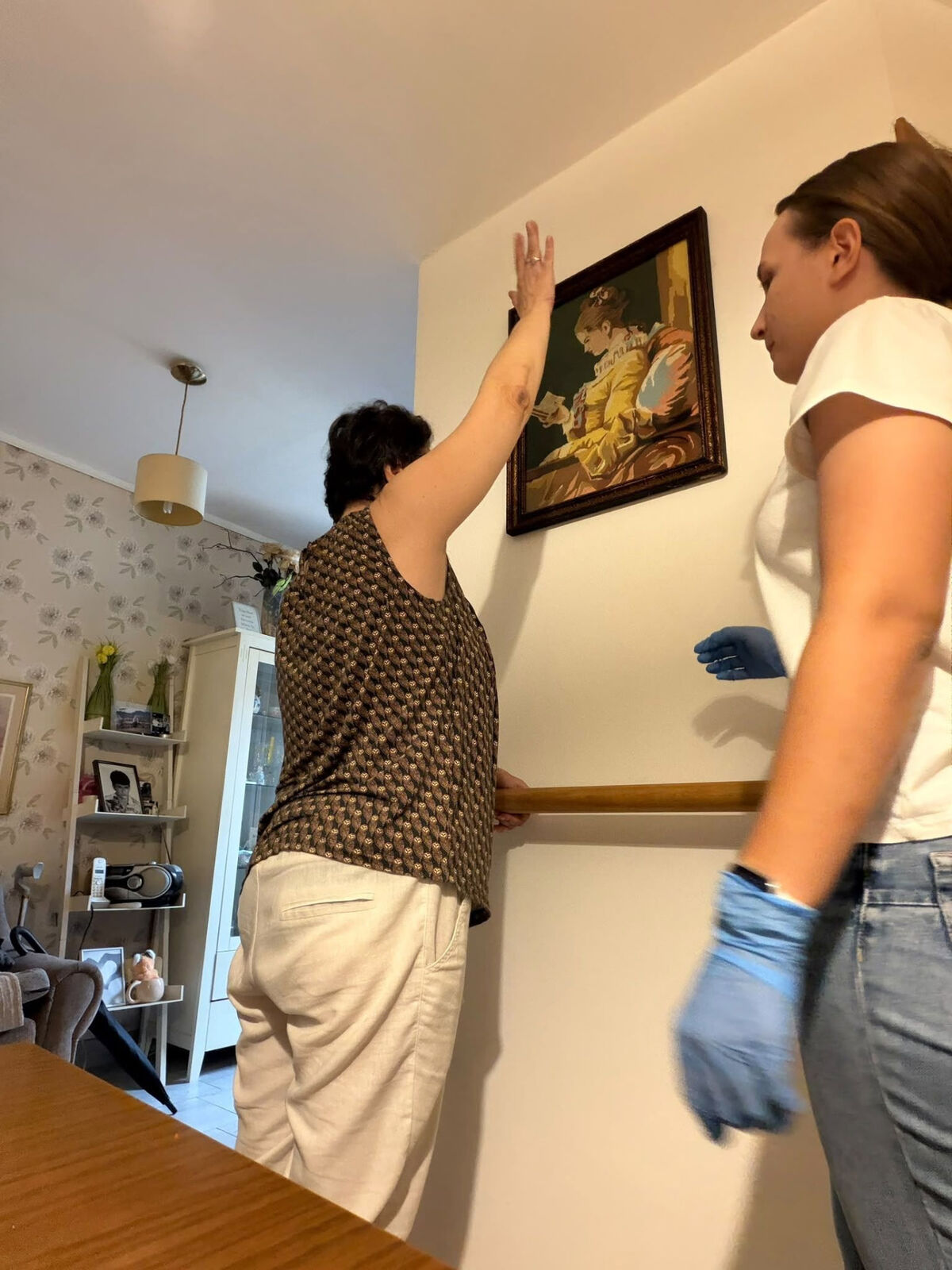 A participant practising a supported arm-reaching exercise with a helper